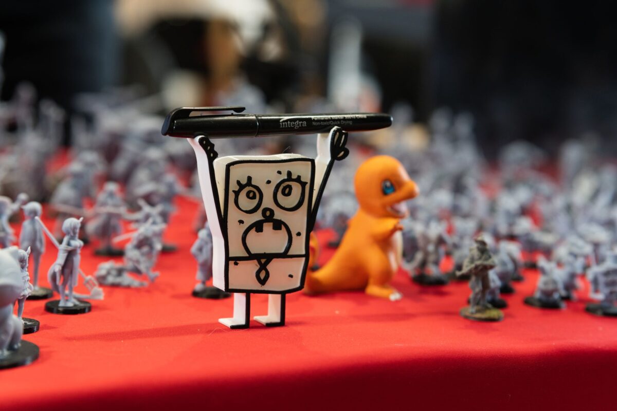 Close-up of assorted figurines and toys displayed on a red table at a convention.