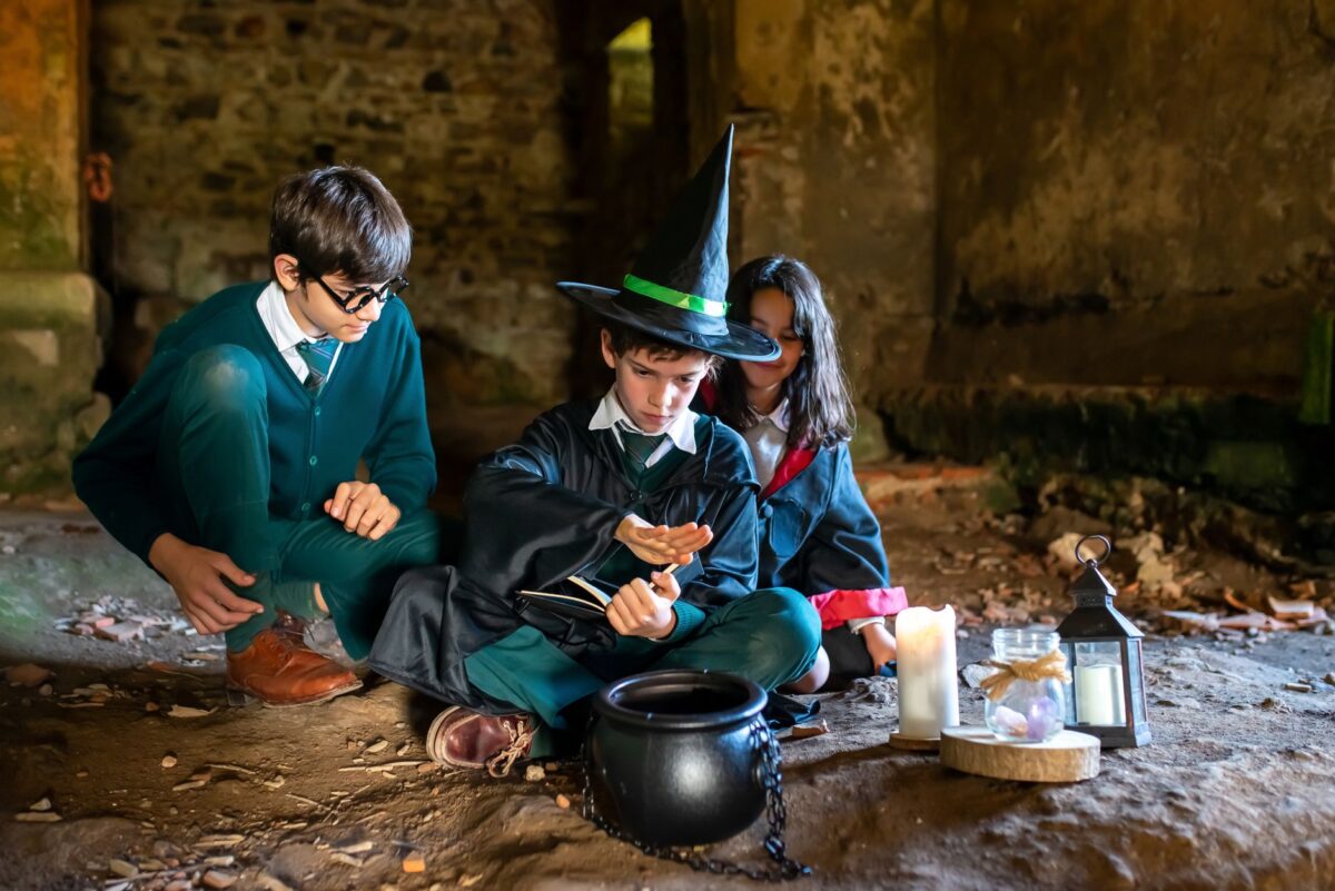 Children dressed as wizards and witches casting spells in an old stone building.