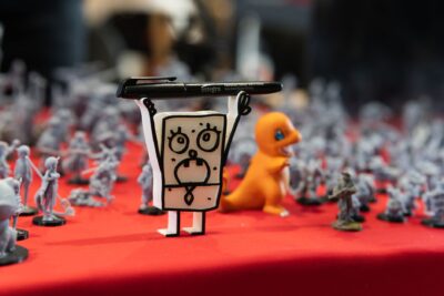 Close-up of assorted figurines and toys displayed on a red table at a convention.